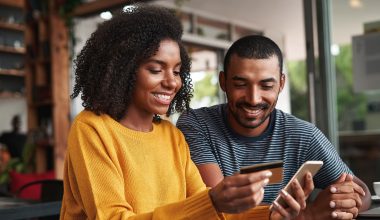 Man looking at his girlfriend shopping online in cafe