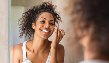 Black girl applying lotion on face