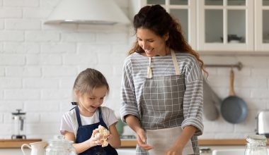 Mother and little daughter kneading dough for domestic pie