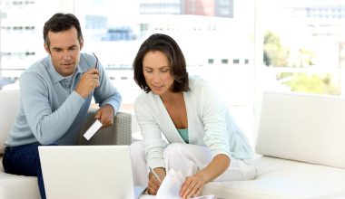 Couple using computer laptop on sofa at home for online s